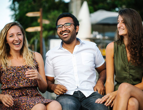 A guy laughing with his girlfriend and her friends who he's meeting for the first time.