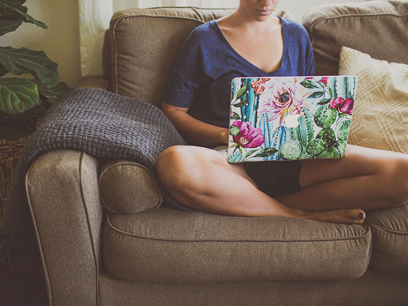 A woman who learned how to write an online dating profile, writing on her computer on the couch.