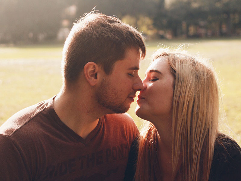 A couple about to have a second date kiss, eyes closed with their lips almost touching.