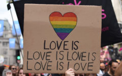 A group of people holding up a sign that says love is love is love is love at a Pride parade.