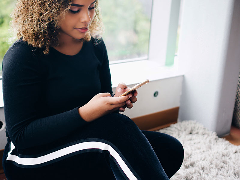 A woman on her phone looking for apps like Tinder on the apple app store.