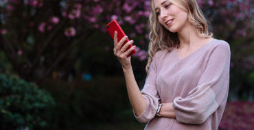 A woman reading Tinder opening lines from men on her phone and smiling.