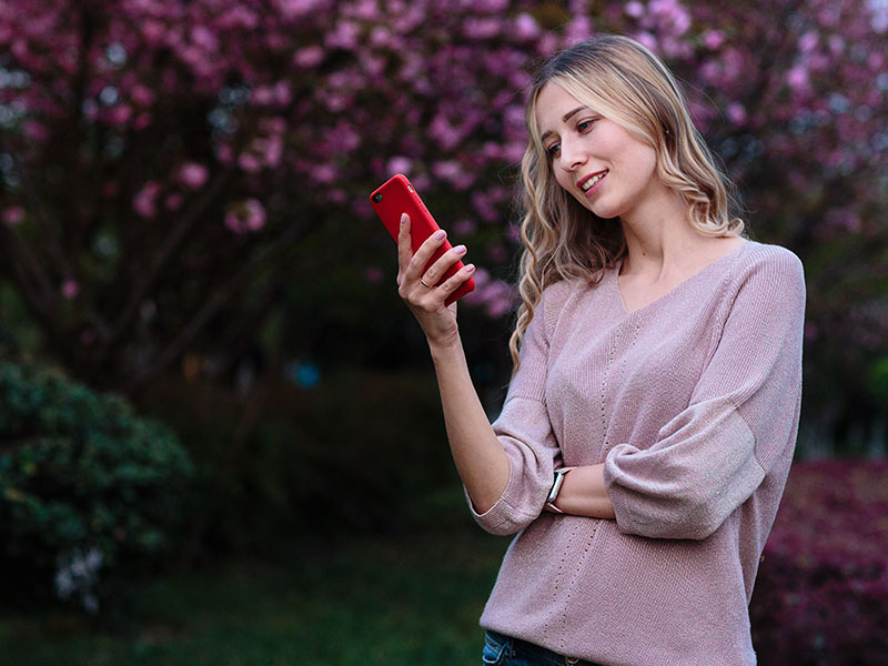 A woman reading Tinder opening lines from men on her phone and smiling.