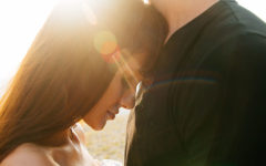 A couple in a healthy relationship hugging in the sunset as the woman closes her eyes and smiles.