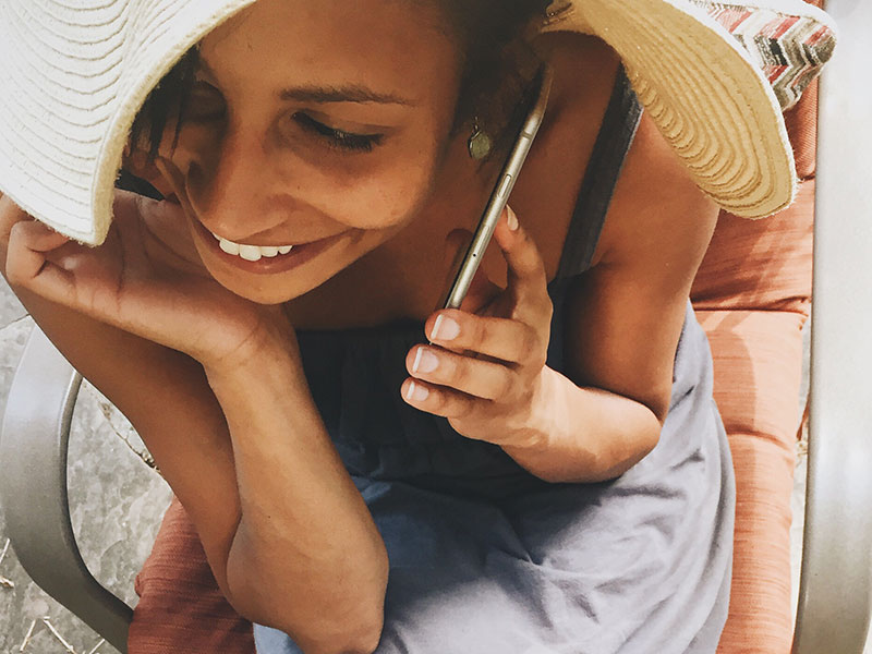 A woman talking on the phone with her boyfriend who's showing signs he miss you, and laughing at his flirting.