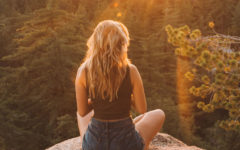 A woman who learned how to build confidence in yourself sitting on a rock in the sun.