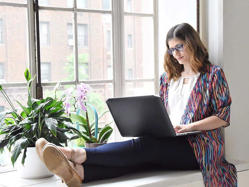 A woman on her computer writing a plenty of fish headline.