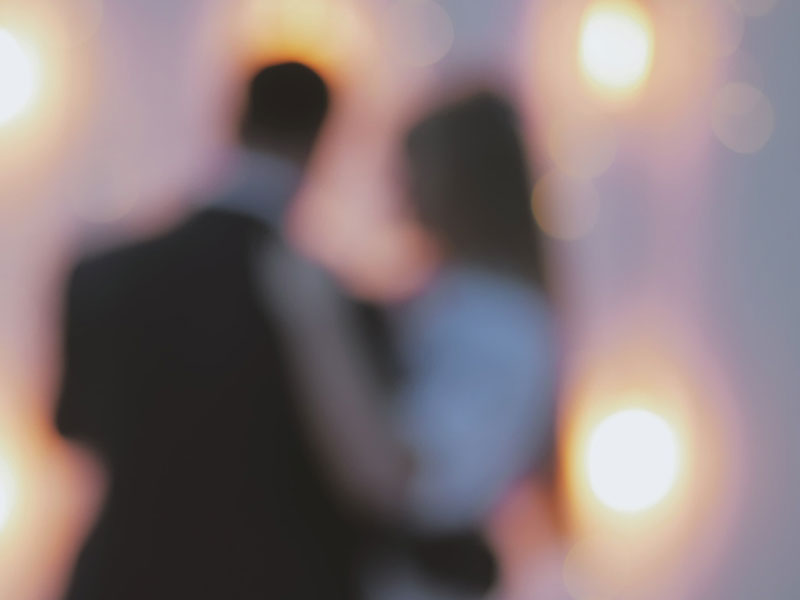 The hazy silhouette of a woman in love with a married man clinging to his side walking down the street.