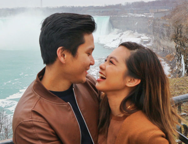 A girl who used these questions to ask a guy you like, laughing with her boyfriend as they take a photo in front of a waterfall.