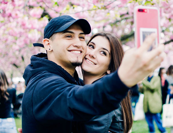 A man who said to himself, I need a girlfriend, smiling with his new girlfriend while they take a selfie at the park.