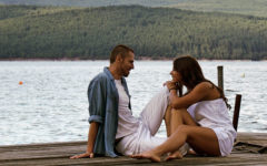 A couple who learned what to do on a first date, leaning in and talking to each other on a dock by a lake.