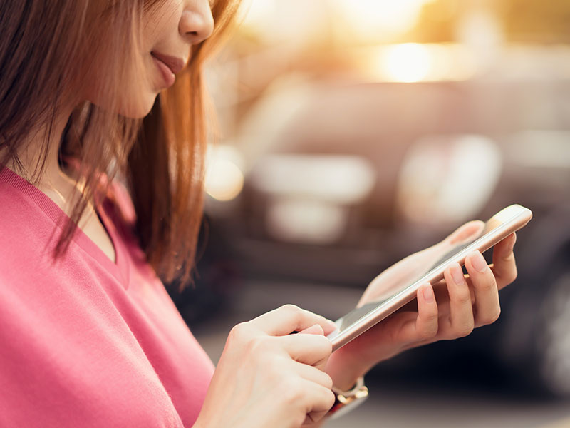 A woman using one of these Tinder alternatives on her phone and smiling as she makes a match.