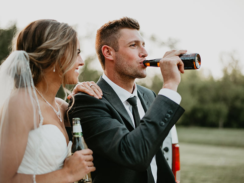 A happy couple drinking beer at their wedding because they know these questions to ask before getting married.