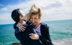 A couple that learned these ways to show love and affection laughing and hugging on the beach.