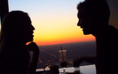 A woman married and flirting with a man as they have a conversation over drinks at sunset.