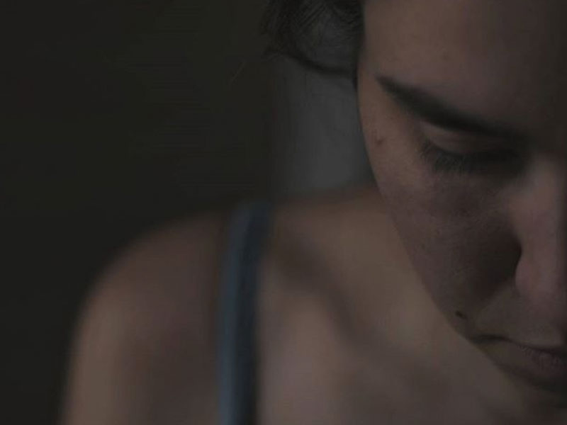 A girl who's heartbroken looking down as she listens to this playlist of the best heartbreak songs and songs about a broken heart to move on.