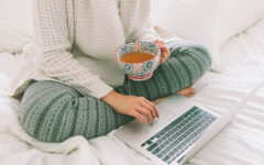 A woman using these dating profile tips to update her online dating profile while she's in bed drinking coffee.