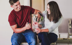 A couple who used these fun things for couples to do laughing and clinking champagne glasses as they have a home date night.