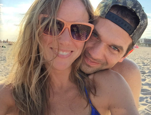 A girl who's dating a shy guy, smiling as her boyfriend grins next to her with his head on her shoulder.