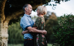 A couple dating after 50, smiling and hugging while looking into each other's eyes.