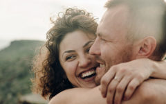 A couple dating in your 40s, smiling and laughing as they hug outside.