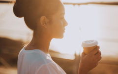 A girl wondering, "Should I break up with my boyfriend" while sipping coffee and watching the sunrise.