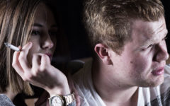 A woman smoking next to her date who thinks smoking is one of his main deal breakers.