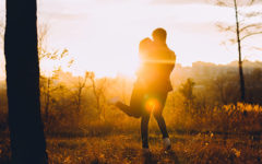 A man who learned when to say I love you, spinning his girlfriend around in a field at sunset.