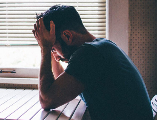 A guy who knows what it means to sabotage relationships, sitting in his kitchen with his head in his hands.