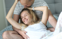 A couple who's mature dating, sitting on the couch laughing and snuggling with each other.