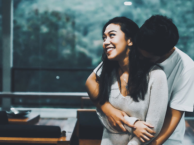 A couple who's showing signs of sexual tension, hugging and flirting at a party.