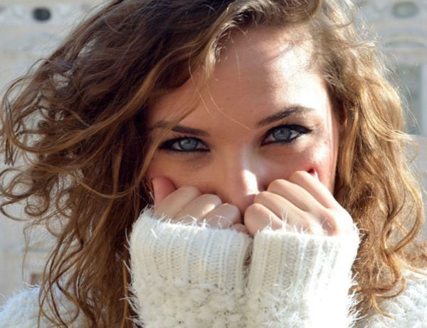 A woman who's showing some of this body language of women, smiling behind her hands.