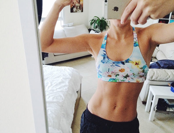 A woman posing in front of her bathroom mirror showing off her abs and doing one of these dating profile no nos.