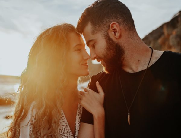 A couple in a twin flame relationship, looking into each other's eyes and souls on the beach at sunset.