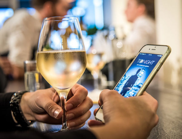 A guy at a bar on his phone, waiting for his Tinder match to show up on a date.