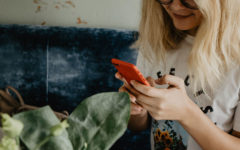 A girl responding to a Tinder first message and laughing on her couch at home.