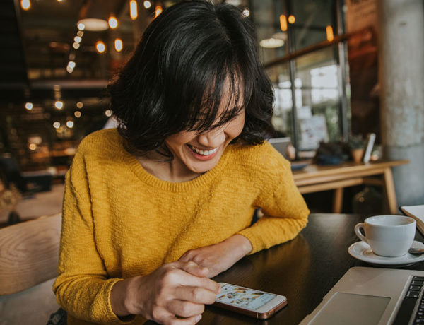 A woman accepting a message from a guy who learned how ot slide into dms without freaking her out, laughing at her phone and texting.