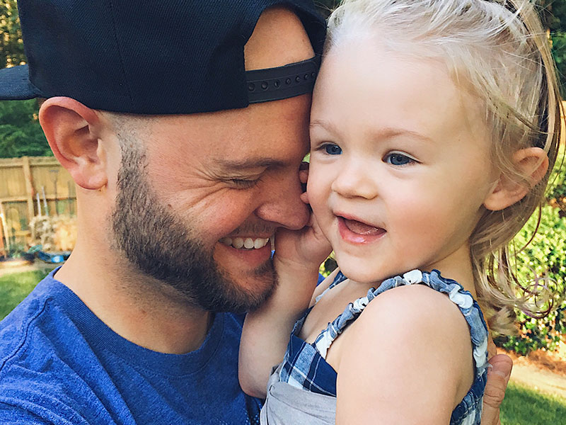 This single dad who's dating is hugging his daughter and laughing.