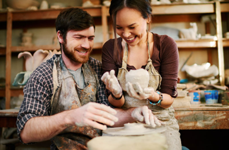 A couple laughing while making cookies at a class, one of the best winter date ideas.