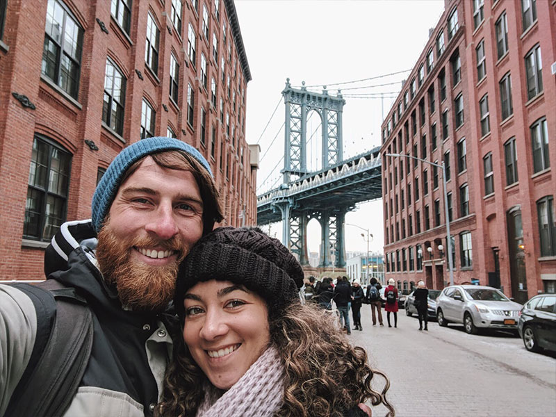 A man who's dating after moving to a new city alone, taking a selfie with his date in front of the Brooklyn bridge.