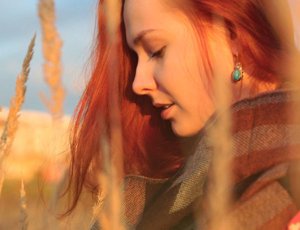 A woman who thinks she's being gaslighted in her relationship thinking about the signs of gaslighting while in a filed wondering what to do.