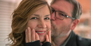 A couple senior dating, smiling together as the man kisses the woman's cheek.
