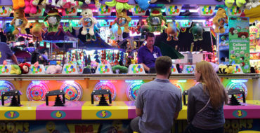 A couple trying to win a stuffed animal at the fair--one of these places to go on a date.