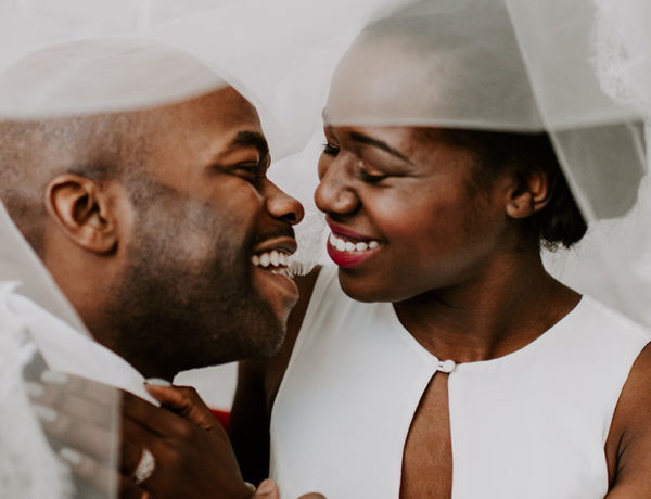 A man and woman who know what it's like to marry your best friend, dressed up for their wedding laughing as they're about to kiss.