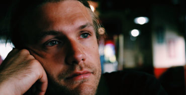 A man going through a divorce, at the bar sipping a drink and thinking.