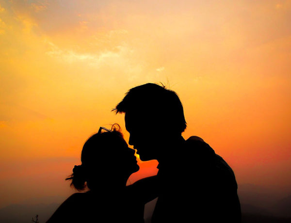 A couple in twin flame love kissing as the sun goes down.