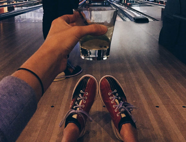 A guy drinking while bowling, using one of these indoor date ideas.