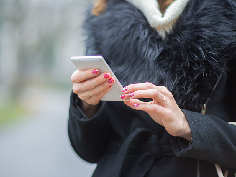 A woman who's wondering is Bumble free, checking the app on her phone outside.