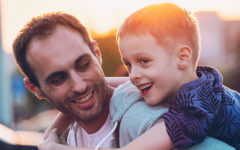A man dating with kids, laughing with his son on his back.