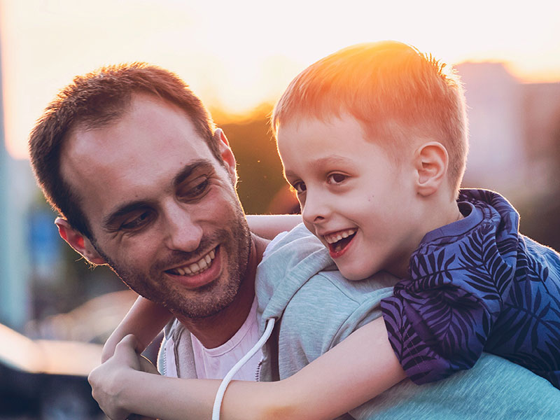 A man dating with kids, laughing with his son on his back.